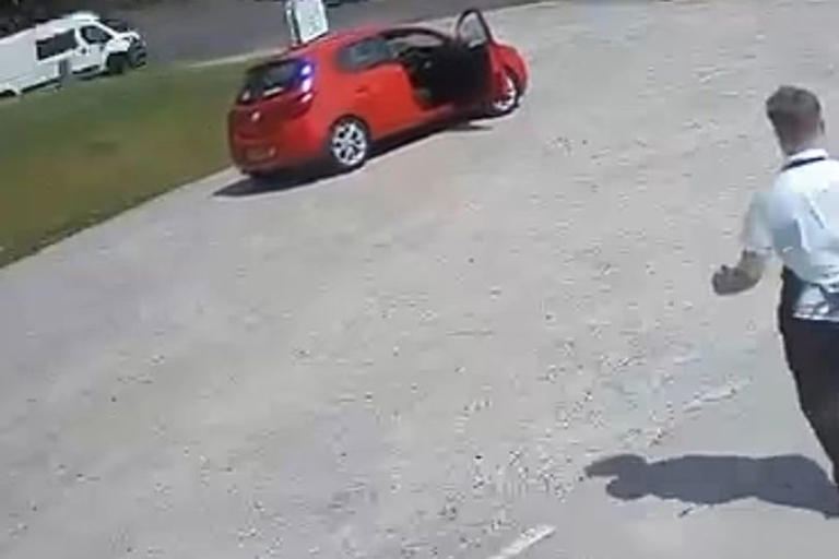 Young man stopping car from rolling away by running after it.